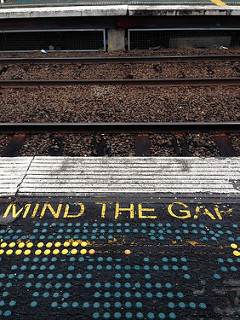 Text on a railway platform that says 'mind the gap'.