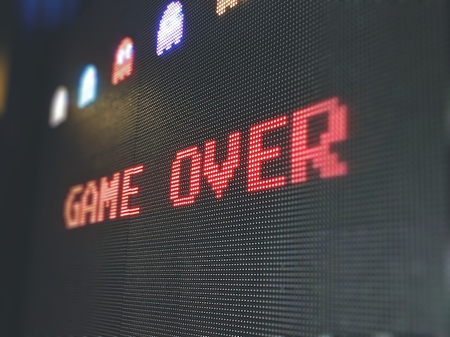 Digital screen that says 'game over', with some PacMan ghosts in the background. 